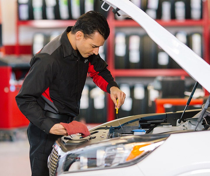 Service technician checking engine oil during a Kia maintenance visit